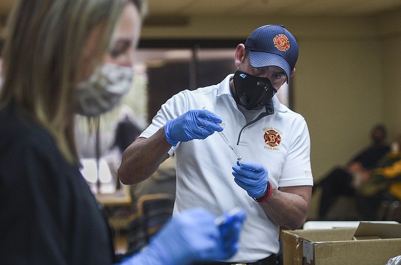 Bella Vista Fire Department Battalion Chief Ronnie Crupper (center) prepares covid-19 vaccines, Friday, February 12, 2021 at Riordan Hall in Bella Vista. (NWA Democrat-Gazette/Charlie Kaijo)