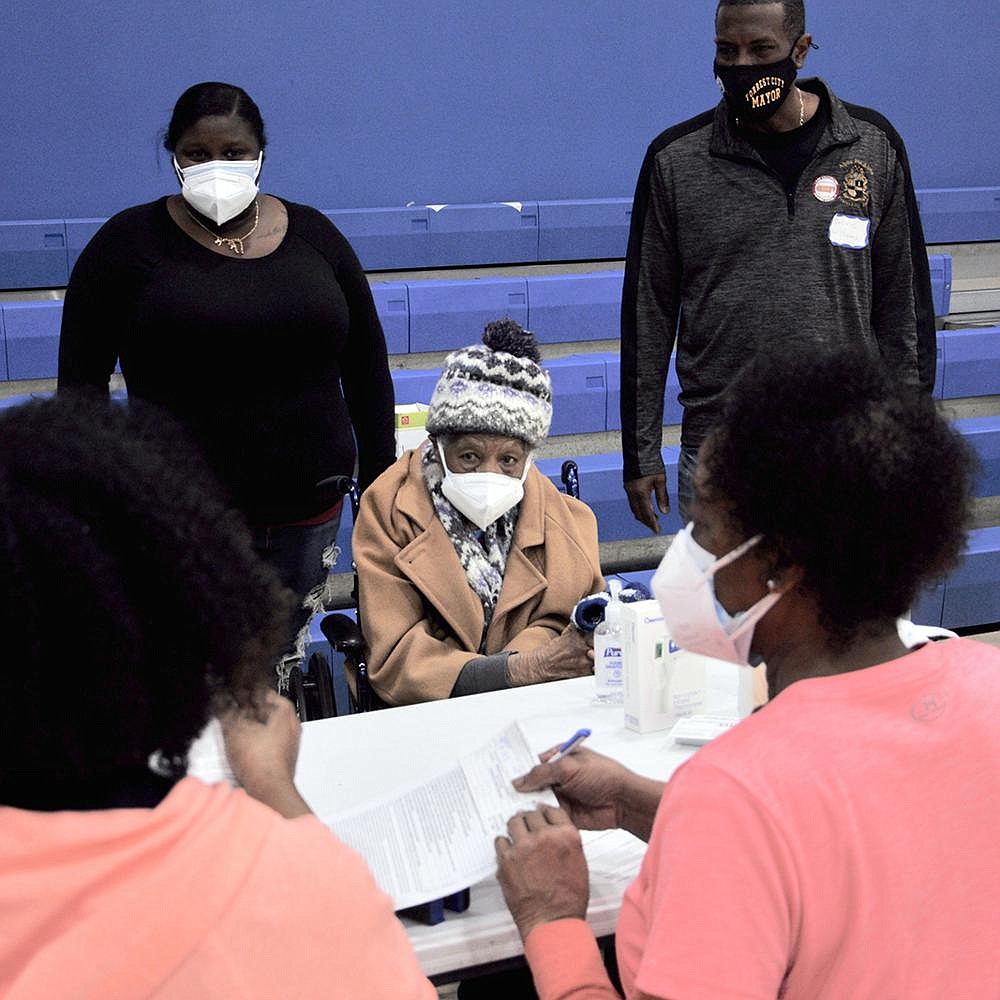 Clara Noble, 103, completes paperwork for her covid-19 vaccination at a clinic earlier this month in
Forrest City. Her daughter said they had been on a pharmacy vaccination waiting list for six weeks.
At right is Forrest City Mayor Cedric Williams, who called the clinic “a godsend for our community.”
(Arkansas Democrat-Gazette/Lara Farrar)