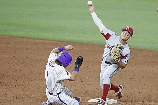 Arkansas second baseman Robert Moore throws as TCU's Elijah Nunez slides into second base during a game Monday, Feb. 22, 2021, in Arlington, Texas. 