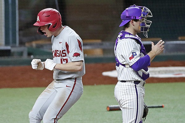 Arkansas designated hitter Brady Slavens (left) celebrates after scoring a run during the ninth inning of a game against TCU on Monday, Feb. 22, 2021, in Arlington, Texas. 