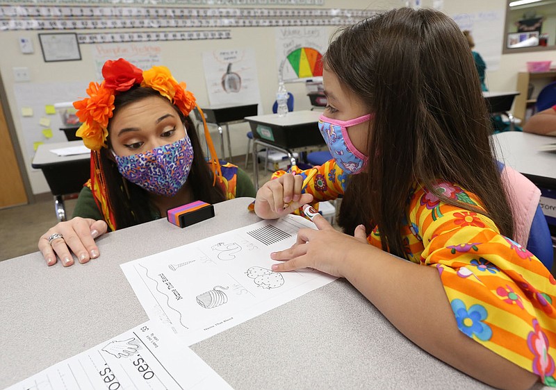 FILE — First grade teacher Kailan Johnson works with Cataleya Orozco-Rodriguez on an english assignment in class at LISA Academy in Springdale in this Oct. 29, 2020 file photo. (NWA Democrat-Gazette/David Gottschalk)