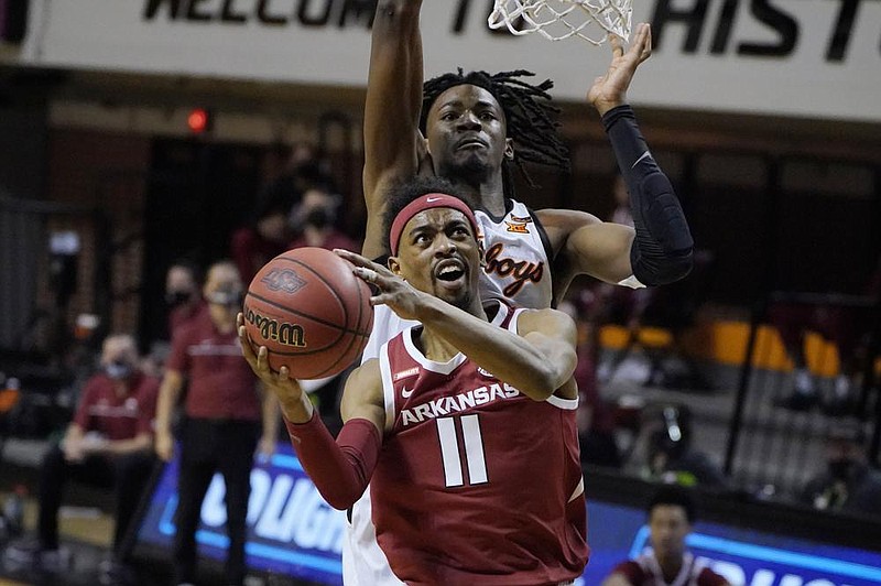 Arkansas guard Jalen Tate (11) goes to the basket in front of Oklahoma State's Kalib Boone, rear, in the first half of an NCAA college basketball game, Saturday, Jan. 30, 2021, in Stillwater, Okla. (AP Photo/Sue Ogrocki)