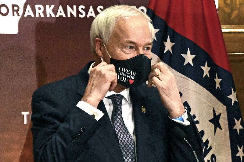 In this July 20, 2020 file photo, Gov. Asa Hutchinson removes his mask before a briefing at the state capitol in Little Rock.  State lawmakers across the country will be convening in 2021 with the continuing COVID-19 pandemic rippling through much of their work and even affecting the way they work. After 10 months of emergency orders and restrictions from governors and local executive officials, some state lawmakers are eager to reassert their power over statewide decisions shaping the way people shop, work, worship and attend school (Staci Vandagriff/The Arkansas Democrat-Gazette via AP)