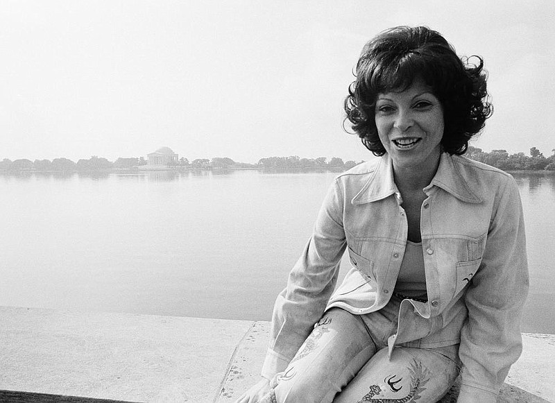 Stripper Fanne Foxe sits on a bridge with the Tidal Basin and the Jefferson Memorial in the background as she plug her book, "The Stripper and the Congress," on Monday, Sept. 8, 1975 in Washington.