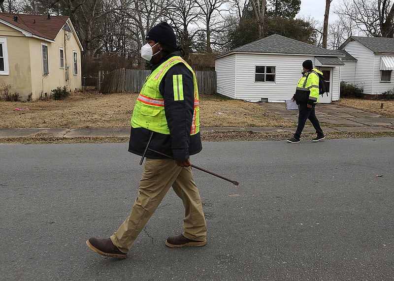 A pair of workers from Liberty Utilities walk through a neighborhood on Thursday, Feb. 25, 2021, in Pine Bluff. The workers, who didn't wish to be identified, said they were going street to street looking for leaks in residential areas. .(Arkansas Democrat-Gazette/Thomas Metthe)