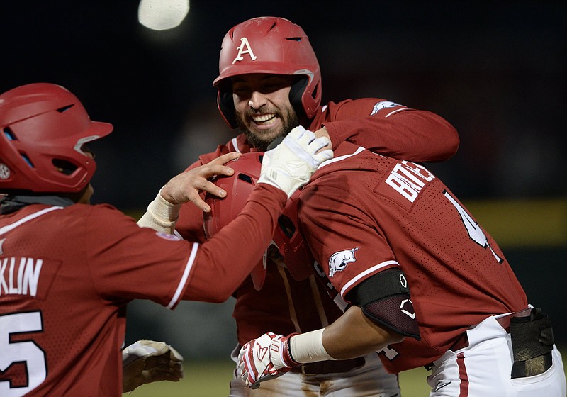 Arkansas’ Casey Opitz (top) and Christian Franklin (left) congratulate teammate Jalen Battles after Battles’ game-winning single in the 
10th inning of Thursday’s game at Baum-Walker Stadium in Fayetteville. More photos available at arkansasonline.com/226semoua.
(NWA Democrat-Gazette/Andy Shupe)