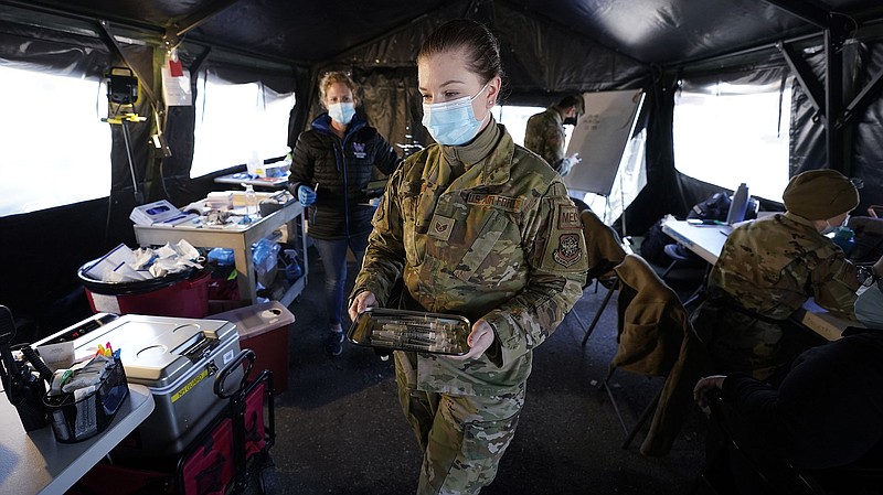 Megan Turgeon, of the New Hampshire National Guard, carries a tray of syringes loaded with the Pfizer COVID-19 vaccine at a clinic set up by the New Hampshire National Guard in the parking lot of Exeter, N.H., High School, Thursday, Feb. 25, 2021, in Exeter. The temporary facility, operating out of a field hospital tent, administers both the Moderna and Pfizer COVID-19 vaccines. (AP Photo/Charles Krupa)