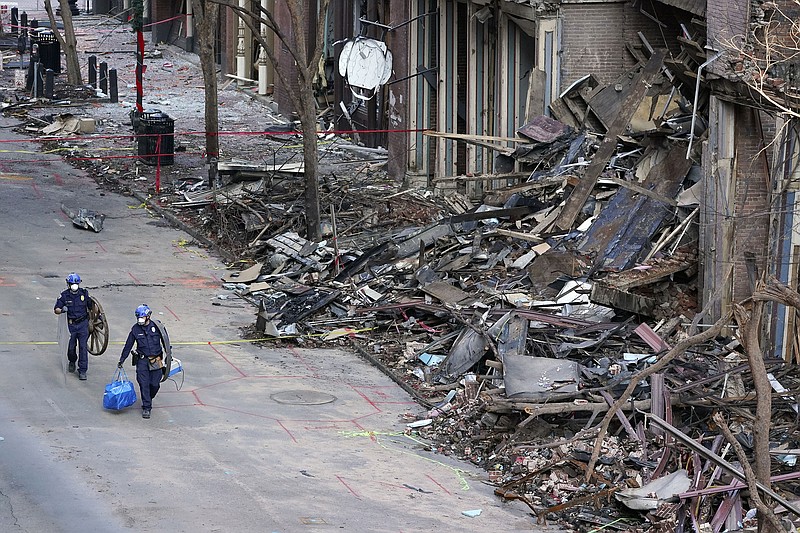 FILE - In this Jan. 4, 2021, file photo, police officers walk past damaged buildings in Nashville, Tenn. The FBI investigation into whether the Nashville bombing was a terrorist act has sparked criticism about a possible racial double standard and drawn questions from downtown business owners whose insurance coverage could be affected by the bureau’s assessment. (AP Photo/Mark Humphrey, File)