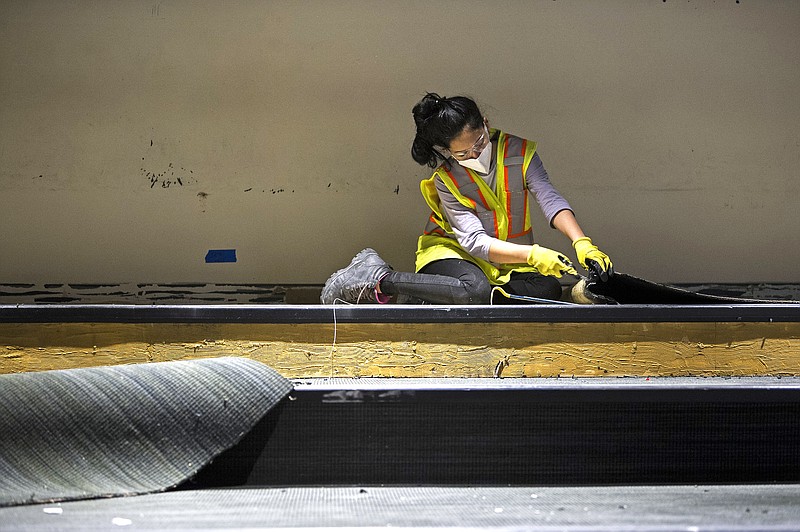 Mariangel Perdomo tears out carpet in the Awesome Science Theatre as she helps repair flood damage at the Museum of Discovery in Little Rock on Saturday, Feb. 27, 2021...(Arkansas Democrat-Gazette/Stephen Swofford)