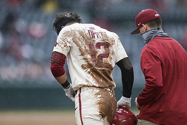 Arkansas catcher Casey Opitz (left) walks off the field with trainer Corey Wood after Opitz was involved in a collision during a game against Southeast Missouri State on Sunday, Feb. 28, 2021, in Fayetteville.