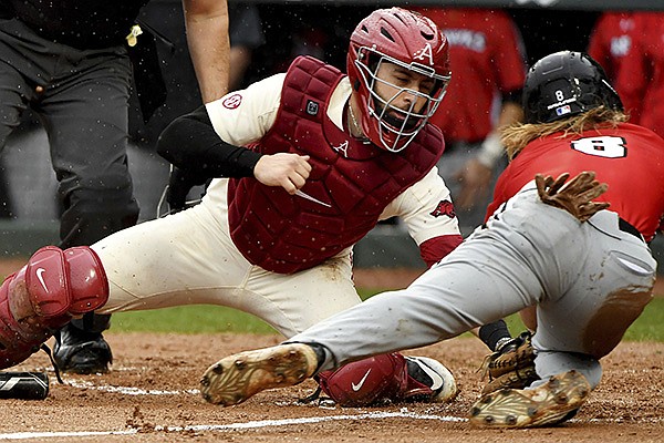 Arkansas catcher Casey Opitz (12) tags out Southeast Missouri St baserunner Ty Stauss (8) out at home during an NCAA baseball game on Sunday, Feb. 28, 2021, in Fayetteville. (AP Photo/Michael Woods)