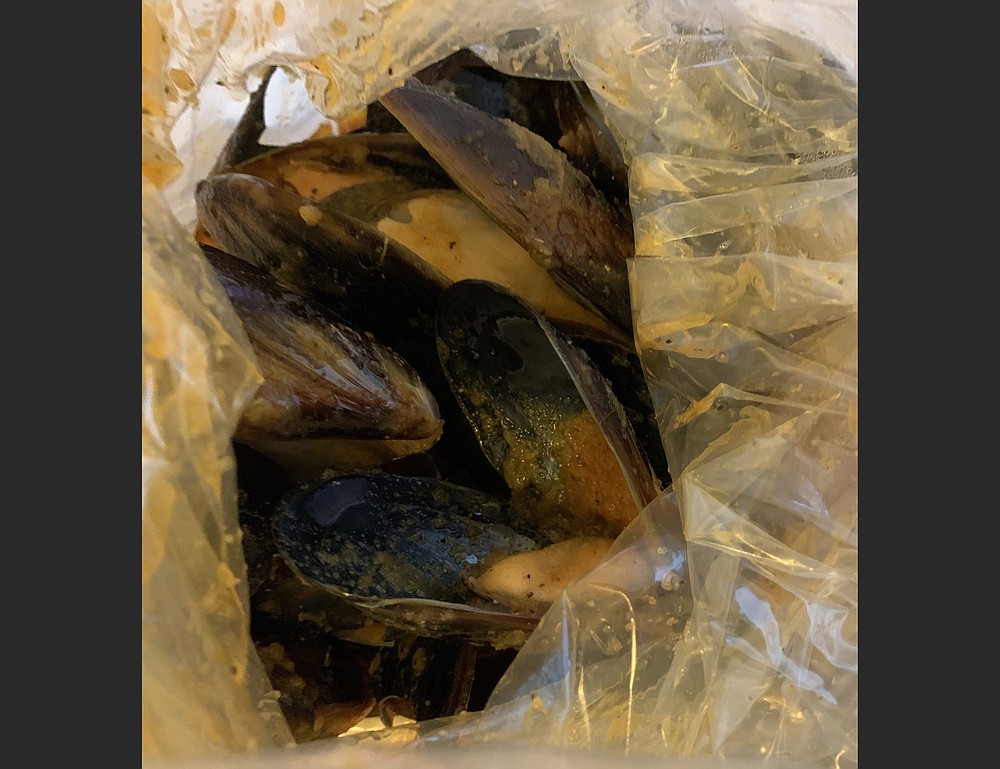 Black mussels in lemon pepper sauce from Juicy Seafood peek out from a double plastic bag. (Arkansas Democrat-Gazette/Eric E. Harrison)