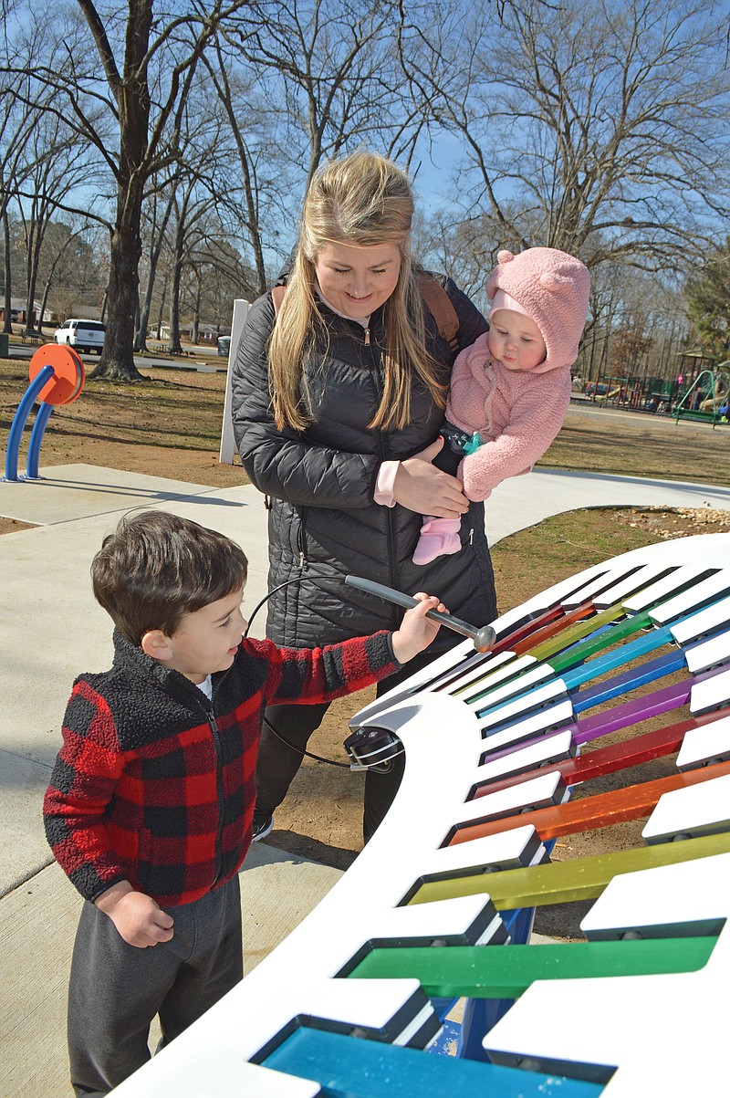 Clark Horton, 3, with his mother, Leah, and sister, Clara, 7 months, plays the xylophone on the Jerry Cooper Sensory Play Trail at Laurel Park in Conway. The trail, sponsored by First Security Bank in Conway, is designed for all ages and abilities.