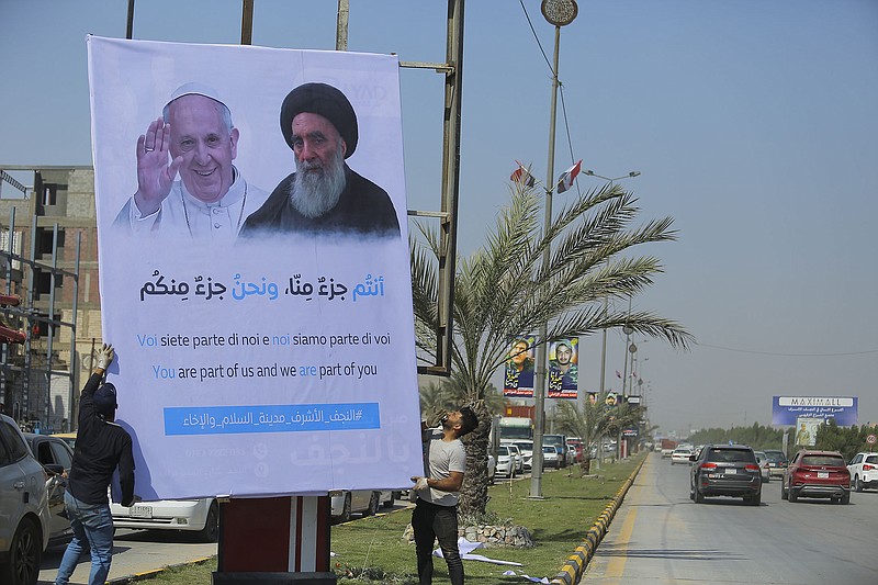 Iraqis put up a poster announcing the upcoming visit of the Pope Francis and a meeting with a revered Shiite Muslim leader, Grand Ayatollah Ali al-Sistani, right, in Najaf, Iraq, Wednesday, Macr 3, 2021. (AP Photo/Anmar Khalil)