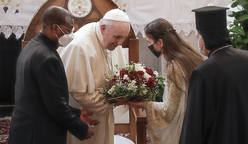 Pope Francis is welcomed with a bouquet Friday as he arrives at the Sayidat al-Nejat (Our Lady of Salvation) Cathedral in Baghdad. More photos at arkansasonline.com/36francis/.
(AP/Andrew Medichini)