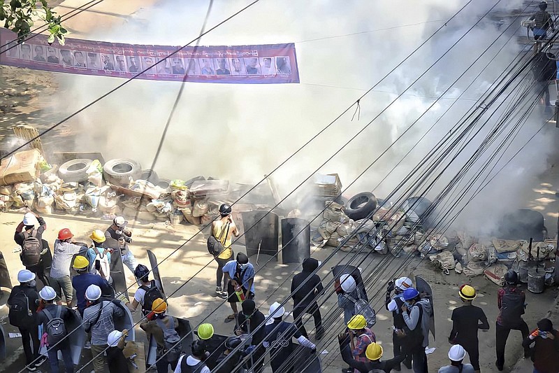 Defiant Burmese protesters behind a barricade face tear gas deployed by security forces Friday in San Chaung township. More photos at arkansasonline.com/36burma/.
(AP)