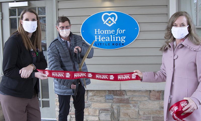 Board members Emily Paul and Kristi Moody hold a ribbon while former board member Dr. Whit Hall  cuts through on 03/02/2021 at a ribbon cutting ceremony for Home for Healing (Arkansas Democrat-Gazette/Cary Jenkins)