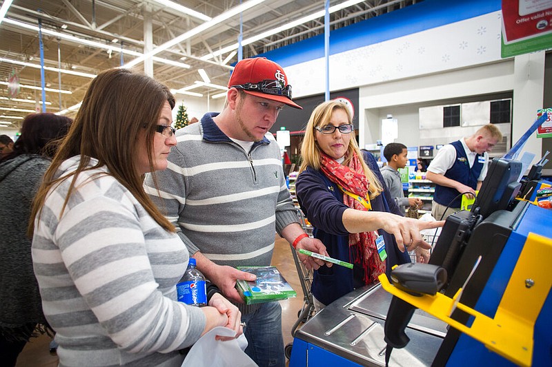 Walmart associate Kathleen Holmes-Smith helps Chris and Mary Finley checkout at the self-checkout lane during Walmart's Black Friday shopping event in Rogers in this Thursday, Nov. 26, 2015, file photo. (Gunnar Rathbun/Invision for Walmart/AP Images)