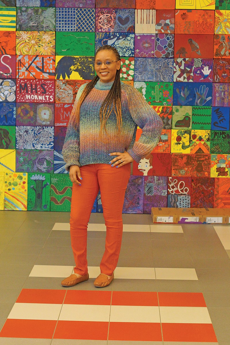 Nakia Morris stands in front of artwork made by Maumelle High School students from boxes their Chromebooks were in. Morris, who goes by Nikki, is the first paraprofessional in Arkansas to become a certified intervener with training in deaf-blindness. She had eye cancer as a toddler and has had a prosthetic eye since she was about 3 years old.