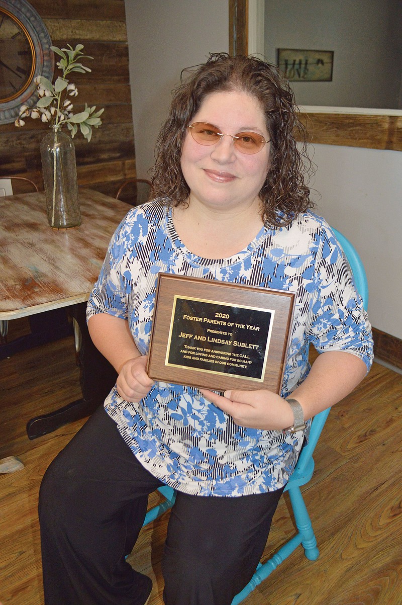 Lindsay Sublett of Bono holds the plaque that she and her husband, Jeff, received as 2020 Foster Parents of the Year. It was awarded by Children of Arkansas Loved for a Lifetime in Conway and Faulkner counties, and she is pictured in The CALL house in Conway. The Subletts have one biological son, two adopted siblings and are fostering-to-adopt a sibling group of five. “I cry at least once a day out of happiness; there is just so much joy,” Lindsay said.