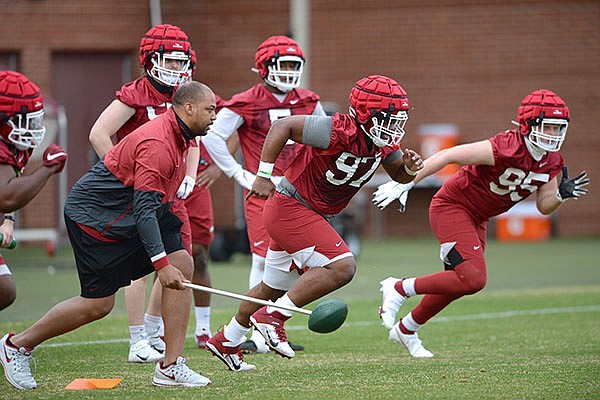Arkansas defensive line coach Jermial Ashley (left) starts a drill Thursday, March 11, 2021, during practice at the university practice facility in Fayetteville.