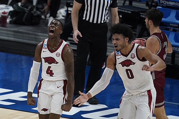 Arkansas' Davonte Davis (4) celebrates with Justin Smith (0) after Davis made a basket as time expired for the first half of a first round game against Colgate at Bankers Life Fieldhouse in the NCAA men's college basketball tournament, Friday, March 19, 2021, in Indianapolis. (AP Photo/Darron Cummings)