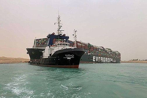 A tugboat navigates in front of the cargo ship Evergreen, which became wedged Wednesday in Egypt’s Suez Canal, blocking traffic in the crucial east-west waterway for global shipping.
(AP/Suez Canal Authority)