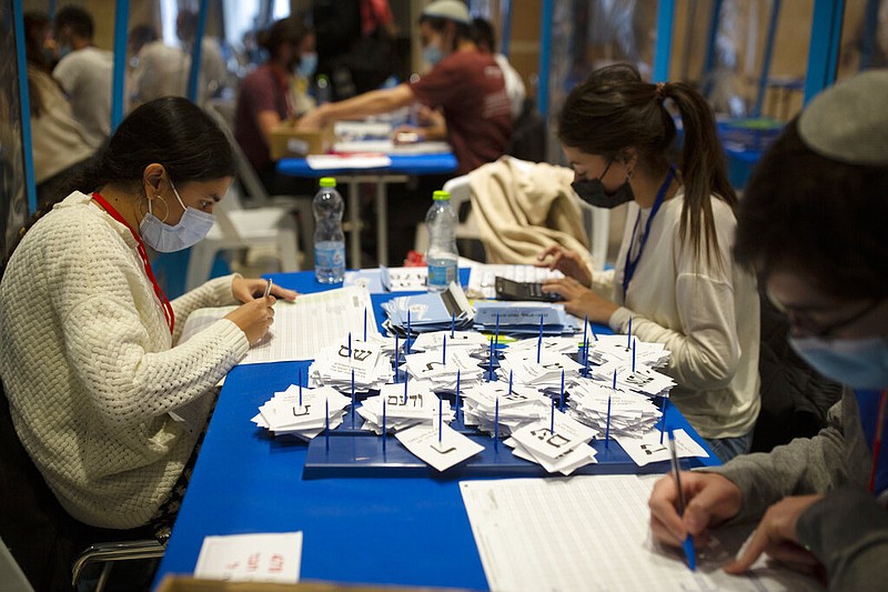 Workers count votes in Israel's national elections at the Knesset in Jerusalem on Thursday, March 25, 2021. The workers were wearing masks and were divided in groups by plastic sheets to help curb the spread of the coronavirus. (AP/Maya Alleruzzo)