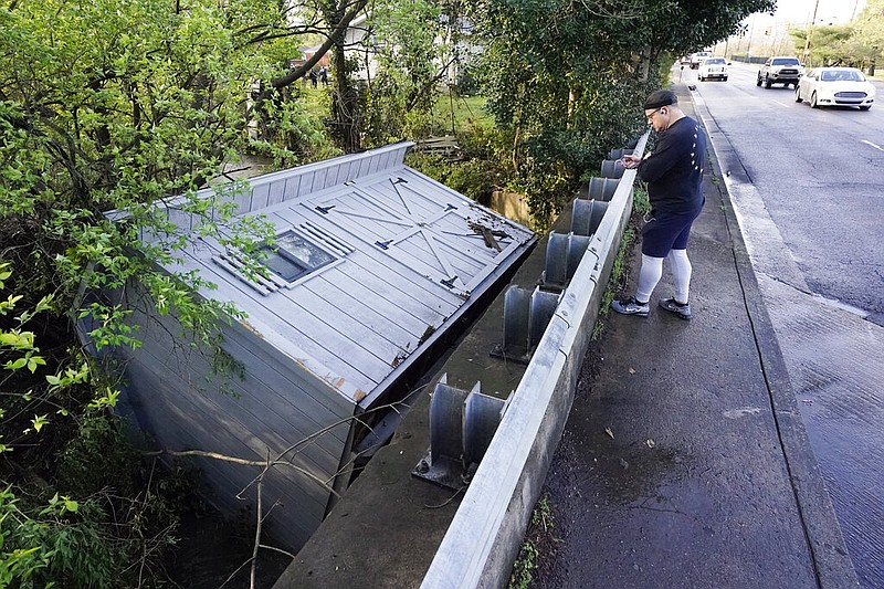 Adam Wirdzek stops Sunday, March 28, 2021, in Nashville to look at a utility building that was carried down a flooded creek. Heavy rains across Tennessee flooded homes and roads as a line of severe storms crossed the state. (AP/Mark Humphrey)