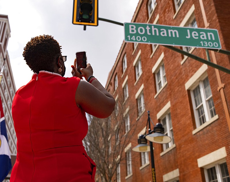Allison Jean takes a photo of the sign for Botham Jean Boulevard in Dallas on Saturday, March 27, 2021. Jean's son, Botham Jean, was murdered in his apartment by a Dallas police officer in September 2018. Botham Jean lived on this portion of the street, formerly known as South Lamar Street. (Juan Figueroa/The Dallas Morning News via AP)