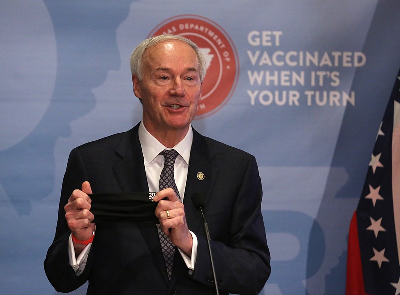 Gov. Asa Hutchinson holds up a mask, saying he would keep wearing his despite his lifting of the statewide mask mandate, during the weekly COVID-19 briefing on Tuesday, March 30, at the state Capitol in Little Rock. (Arkansas Democrat-Gazette/Thomas Metthe)