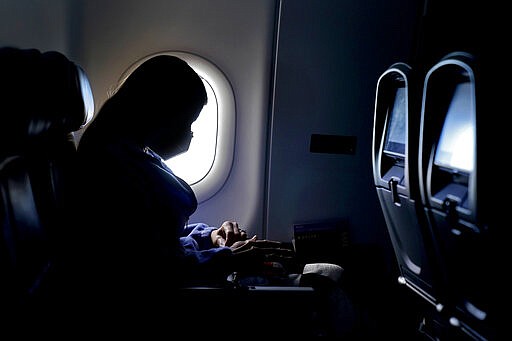 FILE - In this Wednesday, Feb. 3, 2021 file photo, a passenger wears a face mask during an airline flight after taking off from Atlanta. (AP/Charlie Riedel)