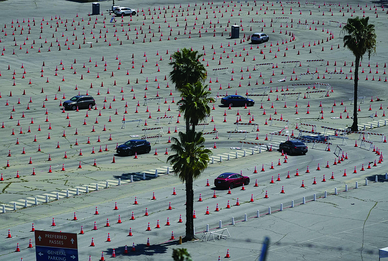 Vehicles follow the cones to line up at the Dodgers Stadium vaccination site Friday in Los Angeles. California has administered nearly 19 million doses, and nearly 6.9 million people are fully vaccinated in a state with almost 40 million residents. But only people 50 and over are eligible statewide to get vaccinated now. More photos at arkansasonline.com/43covid19/.
(AP/Damian Dovarganes)