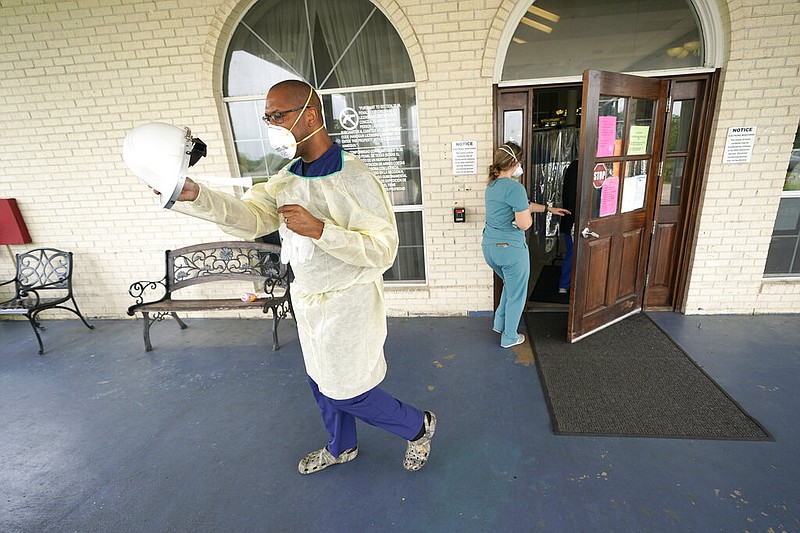 Dr. Robin Armstrong, medical director of The Resort at Texas City (Texas) nursing home, puts on his face shield while demonstrating his full personal protective equipment outside the entrance to the nursing home in this April 7, 2020, file photo. (AP/David J. Phillip)