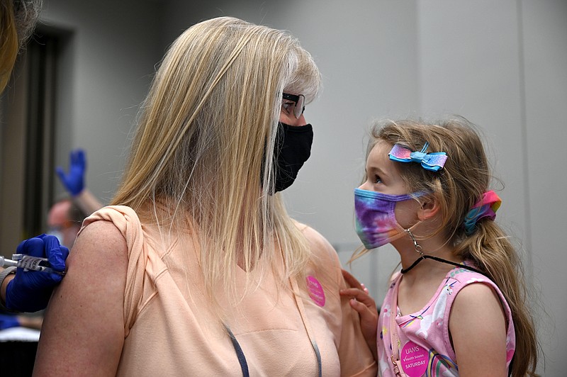 Julie Bauser looks in the eyes of her soon-to-be stepdaughter, Ava Dorobek, 5, as Dorobek distracts her while she receives the covid-19 vaccine during a mass vaccine clinic by UAMS at Simmons Bank Arena in North Little Rock on Saturday, April 10, 2021. (Arkansas Democrat-Gazette/Stephen Swofford)