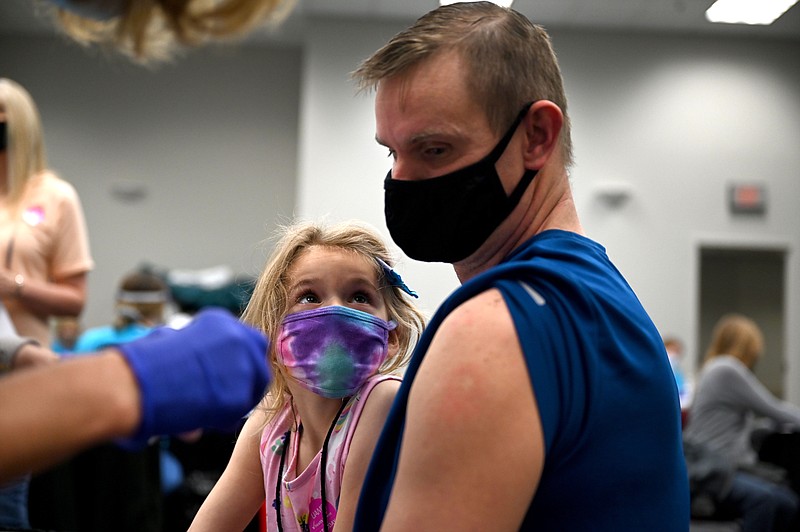 Ava Dorobek, 5, watches as her dad, Kevin, receives a dose of the covid-19 vaccine during a mass vaccine clinic by UAMS at Simmons Bank Arena in North Little Rock on Saturday, April 10, 2021. (Arkansas Democrat-Gazette/Stephen Swofford)