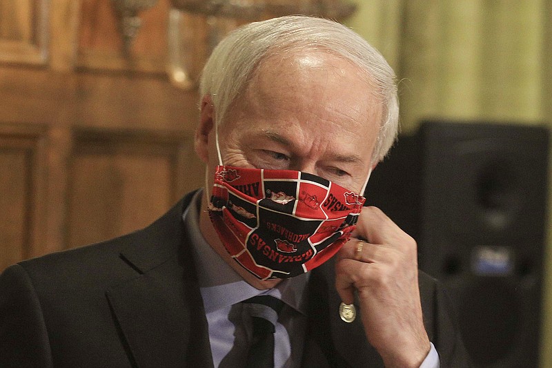 In this April 27, 2020, file photo, Gov. Asa Hutchinson takes off his Arkansas Razorbacks facemark as he arrives for the daily coronavirus briefing at the state Capitol in Little Rock. A longtime abortion opponent who once opposed allowing gay couples to be foster parents, Gov. Hutchinson is the unlikeliest figure to complain about bills on the "culture wars" reaching his desk. (Staton Breidenthal/The Arkansas Democrat-Gazette via AP)