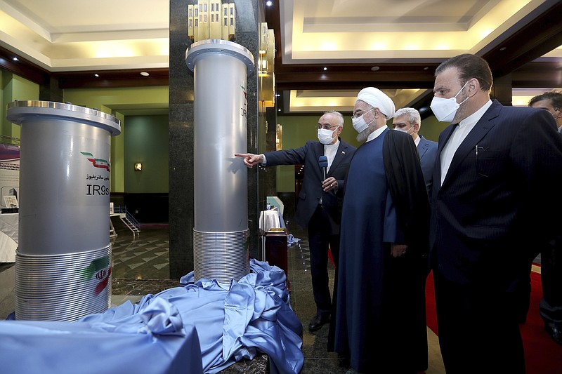 In this photo released by the official website of the office of the Iranian Presidency, President Hassan Rouhani, second right, listens to head of the Atomic Energy Organization of Iran Ali Akbar Salehi while visiting an exhibition of Iran's new nuclear achievements in Tehran, Iran, Saturday, April 10, 2021. Iran said Saturday it has begun mechanical tests on its newest advanced nuclear centrifuge, even as the five world powers that remain in a foundering 2015 nuclear deal with Iran attempt to bring the U.S. back into the agreement. (Iranian Presidency Office via AP)