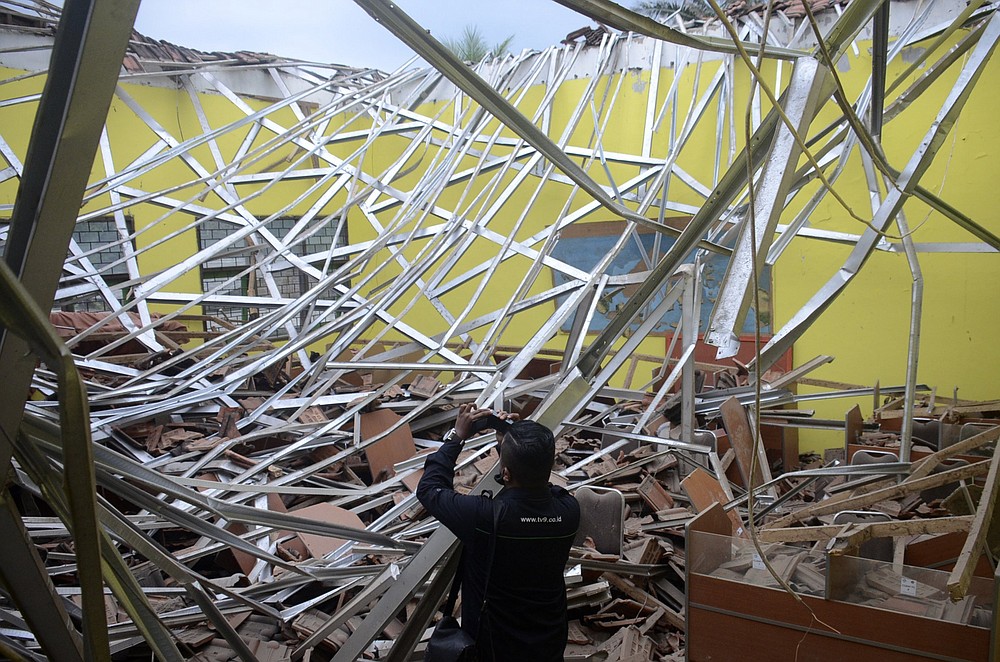 Un journaliste prend une vidéo des dégâts causés à une salle de classe après le tremblement de terre de samedi dans le district de Malang, dans la province indonésienne de Java oriental.  (AP / Hendra Permana)
