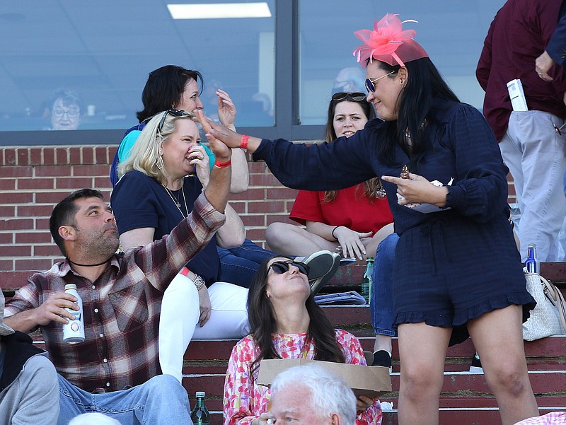Elizabeth Hampton (right) of Bentonville high-fives Kevin Cole (left) of Gravette after their horse won the sixth race on Saturday, April 10, 2021, during Arkansas Derby day at Oaklawn in Hot Springs. .More photos at www.arkansasonline.com/411derby/.(Arkansas Democrat-Gazette/Thomas Metthe)