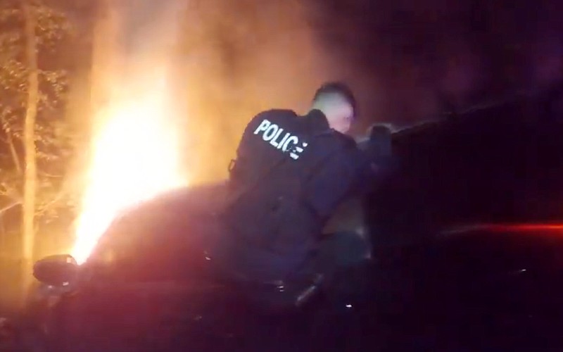 Tontitown officer Garrett Henry climbs into a burning vehicle to assist the driver in a screenshot from officer Rebecca Martisâ€™ body camera. (Courtesy/Tontitown Police Department)