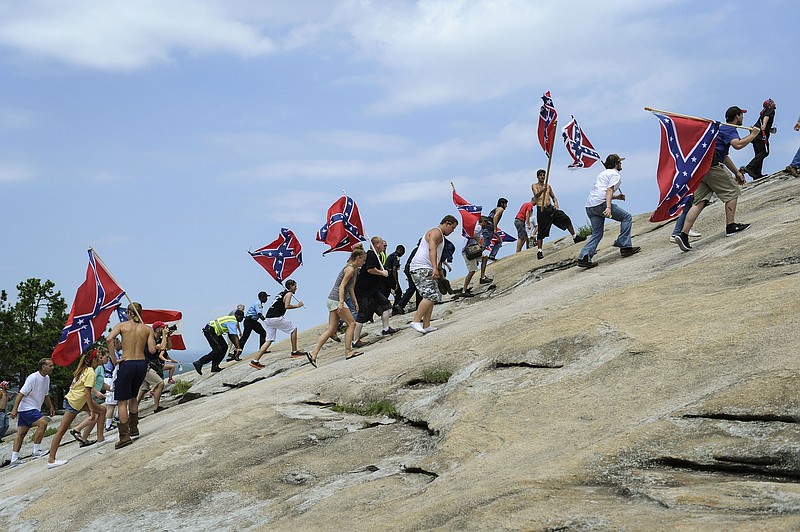 FILE - In this Aug. 1, 2015, file photo, Confederate flag supporters climb Stone Mountain to protest what they believe is an attack on their Southern heritage during a rally at Stone Mountain Park in Stone Mountain, Ga.  The Stone Mountain Memorial Association has denied a gathering permit from the Sons of Confederate Veterans, who were looking to host their annual Confederate Memorial Day service at Stone Mountain Park outside Atlanta.  The gathering was slated for Saturday, April 17, 2021,  but a March 31 letter from memorial association CEO Bill Stephens denied the necessary permit, The Atlanta Journal-Constitution reported.  (AP Photo/John Amis, File)