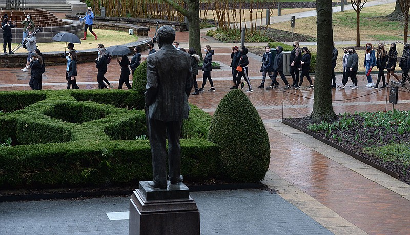 A large group of University of Arkansas students and members of the campus community march Saturday, March 13, 2021, past a statue of J. William Fulbright near Old Main during a rally on the university campus in Fayetteville.  (NWA Democrat-Gazette/Andy Shupe)