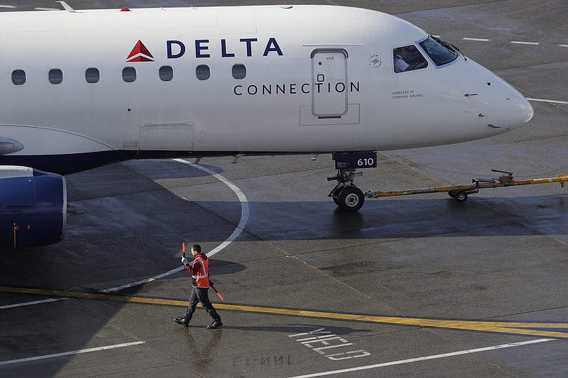 A ramp worker guides a Delta Air Lines plane at Seattle-Tacoma International Airport in Seattle in this file photo. Delta Air Lines lost $1.2 billion in the first quarter, but executives said Thursday that the airline could be profi table by late summer.
(AP)