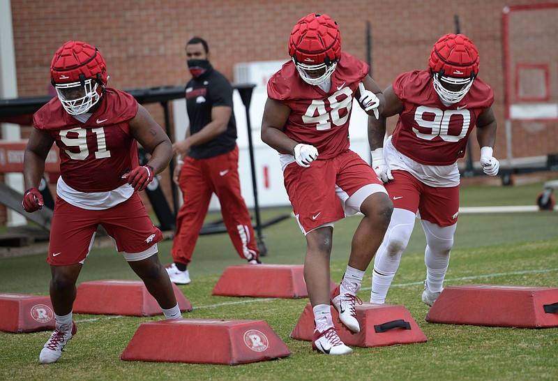 Defensive linemen Taurean Carter (left) joins Nicholas Fulwider (center) and Marcus Miller in a drill during a recent spring practice. Carter has had a lot of work on the Arkansas defense first unit and said he has progressed with the encouragement of coaches. More photos at arkansasonline.com/416uapractice/
(NWA Democrat-Gazette/Andy Shupe)