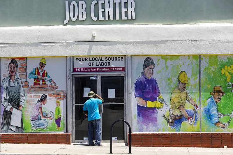 FILE - In this May 7, 2020, file photo, a person looks inside the closed doors of the Pasadena Community Job Center in Pasadena, Calif., during the coronavirus outbreak. (AP/Damian Dovarganes, File)