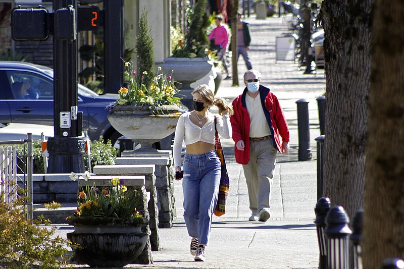 Residents wearing masks walk through downtown Lake Oswego, Ore., on Sunday, April 11, 2021. Tens of thousands of Oregon residents are angry about a proposal to make permanent an emergency rule that requires masks and social distancing in the state's businesses and schools to prevent the spread of covid-19. (AP/Gillian Flaccus)