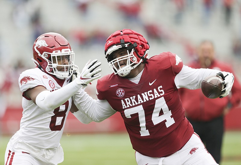 Arkansas offensive lineman Jalen St. John (74) pushes off wide receiver Mike Woods (8) as he carries the ball, Saturday, April 17, 2021 during the fourth quarter of the Red-White spring football game at Razorback Stadium in Fayetteville. Check out nwaonline.com/210418Daily/ for today's photo gallery. .(NWA Democrat-Gazette/Charlie Kaijo)