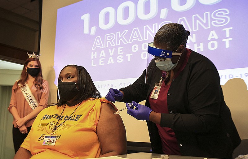 Sharian Kwansai, state Department of Health nurse manager for public health, gives Sheryl Moore a covid-19 shot Thursday to mark the millionth Arkansan vaccinated milestone. Miss Arkansas Darynne Dahlem (background) spoke at the event.
(Arkansas Democrat-Gazette/ Staton Breidenthal)