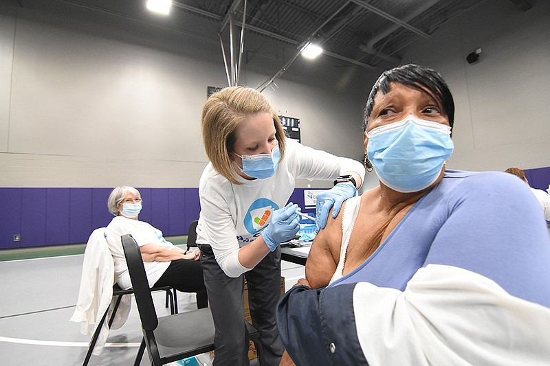 Camille Wilson (left), a registered for CHI St. Vincent, gives Margaret Rincher of Little Rock her first dose of the coronavirus vaccine as Jhonnixy Solis, a volunteer translator, watches Friday, April 23, 2021, at Little Rock Southwest High School. The clinic, hosted by the City of Little Rock, CHI St. Vincent, the Mexican Consulate and the Little Rock School District, focused on the Spanish-speaking members of the community, but was open to anyone eligible to receive the vaccine. See more photos at arkansasonline.com/424vaccine/. (Arkansas Democrat-Gazette/Staci Vandagriff)